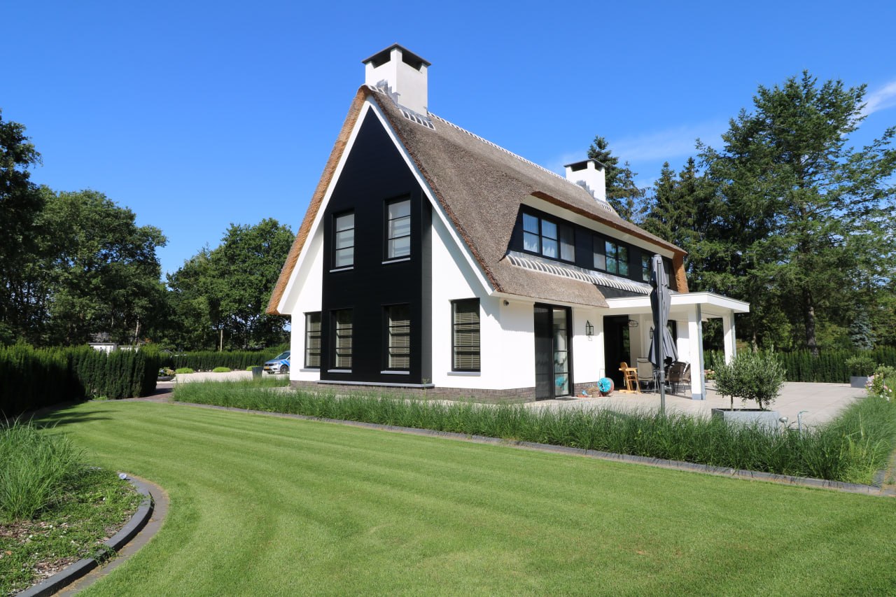 Rietgedekte woning met witte gevels en zwarte accenten